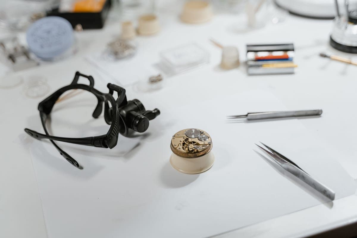 A watch and small tools on a workbench in warm light